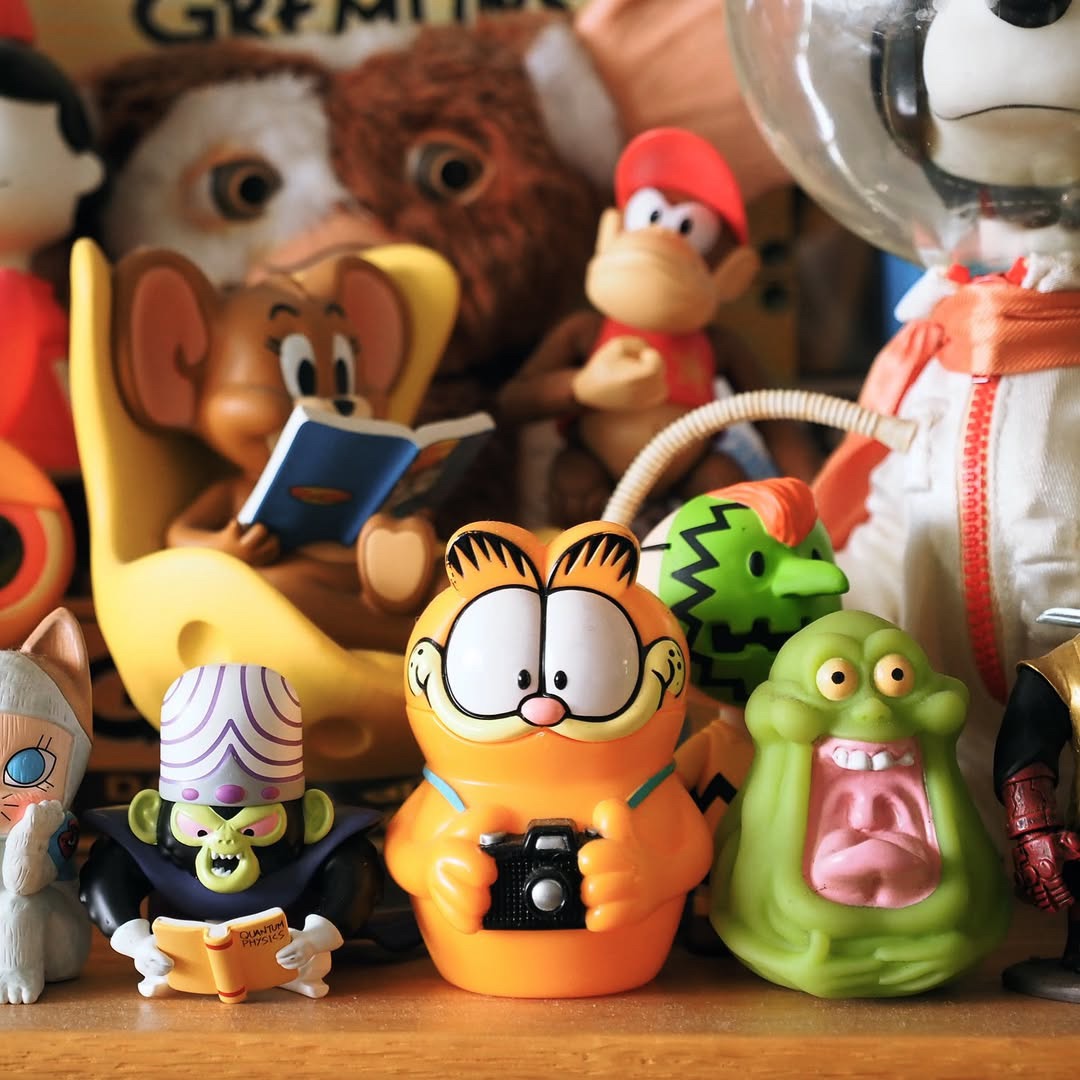 谁懂啊！这只抱着相机的加菲猫，直接把我拉回了那个要等胶卷冲洗的年代。  它是1997年AGFA爱克发的联名底片盒，本身就是胶卷时代的活文物。 抱着相机的姿势，不是刻意摆拍，更像刚按下快门的瞬间，定格了那种“按下快门，一切未知”的心情。 中空可开的设计，原本是用来装胶卷底片，后来也能塞零钱、小首饰，或是那些“暂时放着，之后再看”的零碎。  就像当年拍完照，要等好几天才能看到成片的期待感，藏在这只加菲...